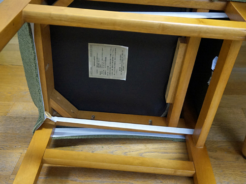 しゅくしゅ素材の伸びる椅子カバーを取り付けて、椅子の裏側のベルトをセットするところ